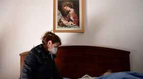 A woman talks to her 80-year-old mother, who is in bed with potential symptoms of COVID-19.(Piero Cruciatti/AFP/Getty Images)