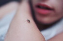 female with a mosquito on her arm. 