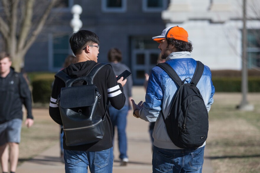 Two Missouri State University students walk toward Carrington Hall.