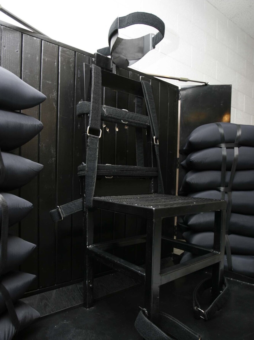 The execution chamber at the Utah State Prison after Ronnie Lee Gardner was executed by firing squad in Draper, Utah, in 2010 for aggravated murder. Four bullet holes are visible in the wood panel behind the chair. [Trent Nelson / AP]