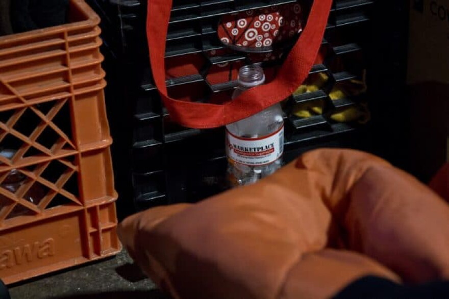 A water bottle is filled with needles at an encampment beneath an overpass at Emerald and Lehigh streets. (Kimberly Paynter/WHYY)