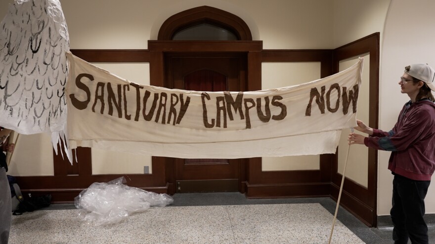 A large banner reading "SANCTUARY CAMPUS NOW" 