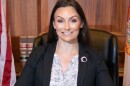 Nikki Fried poses for a picture at her desk flanked by state and national flags