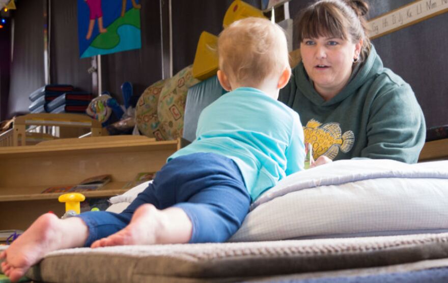 Gretchen Boone flips through a picture book for an infant at the Gold Creek Child Development Center in Juneau on May 11, 2018. Boone is the center’s director. (Photo by Jeremy Hsieh/KTOO)