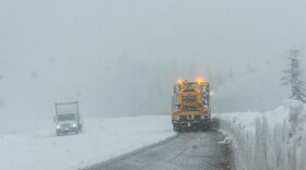 A snowplow clears a few inches of snow off a road