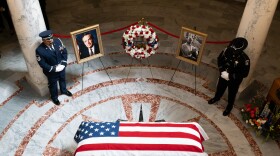 Two officers stand watch over a flag-draped casket.