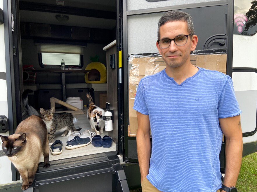 Mike Johansen stands by the door of the camping trailer where the couple is living while they wait for construction on their new home to be finished. [Andrea Johansen]