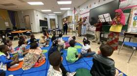A classroom of students listens to a musical performance.