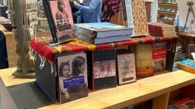 A wooden stand supports layers of books, mostly about Indigenous people.