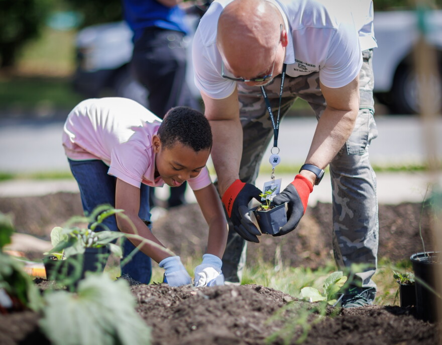 Ezke Black, 7, and McGirt-Horton librarian Greg Bargeman create edible landscaping at the Renaissance Center on Phillips Avenue on May 5, 2026. The garden installation is a collaboration by several organizations, including Try Healthy, Out of the Garden Project, Guilford County Food Action Network, and Recipe for Success at UNCG.