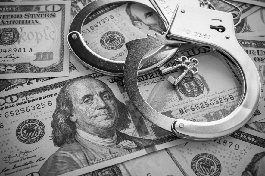 Pair of metal police handcuffs on US dollar banknotes 