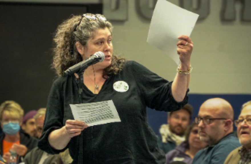 Amelia Kirby reads from Bureau of Prison documents at a public meeting in late March.