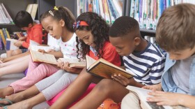 School kids sitting on cushions and reading books in a library