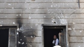 A Free Syrian Army fighter looks out from the window of a burnt-out police station in  Aleppo after it was overrun by rebel fighters last week.