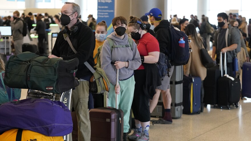 Travelers wait in the ticketing line at Salt Lake City International Airport on Monday. There have been thousands of flight delays and cancellations as the omicron variant spreads across the country. Unionized flight attendants are wary of new CDC guidelines that shorten the isolation period.