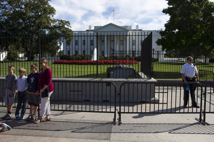 A Secret Service police officer stands nears tourists outside the White House on Monday.