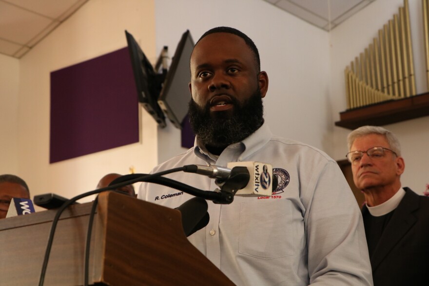 A man in a button down shirt looks toward the camera.