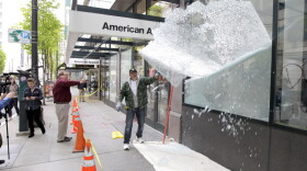 worker removes a shattered window from a Nike Town store on Tuesday after after it was damaged during May Day protests in downtown Seattle.