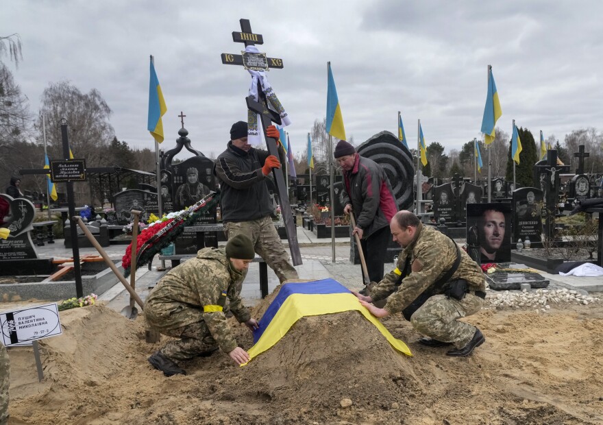 <strong>March 5:</strong> Ukrainian paramedics cover with the National flag the grave of their colleague Valentyna Pushych killed by Russian troops in a cemetery in Kyiv, Ukraine.