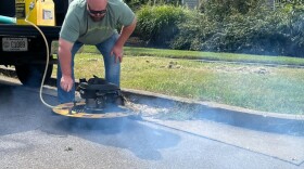 A worker demonstrates the smoke machine that will be used to detect odors in Lexington's sewer system.