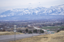 A road leading toward a valley with snowy mountains in the background.