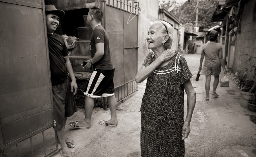 Narcisa Claveria laughs with neighbors in this 2019 photo. Even in the coronavirus pandemic, she goes out, wearing a mask. "I'd rather die in the streets," she says, "than stay dying of sadness at home."