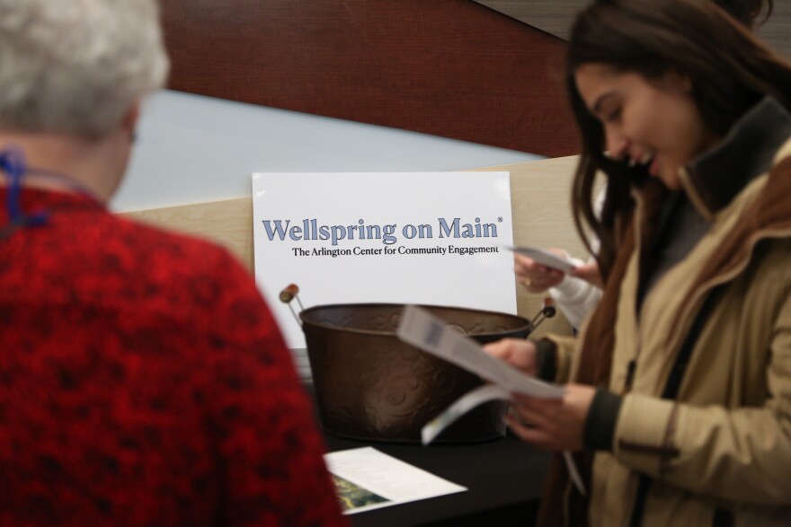 Attendees read pamphlets for the Wellspring on Main during the "Gathering at the Wellspring: A Vision for Arlington's Future" event.