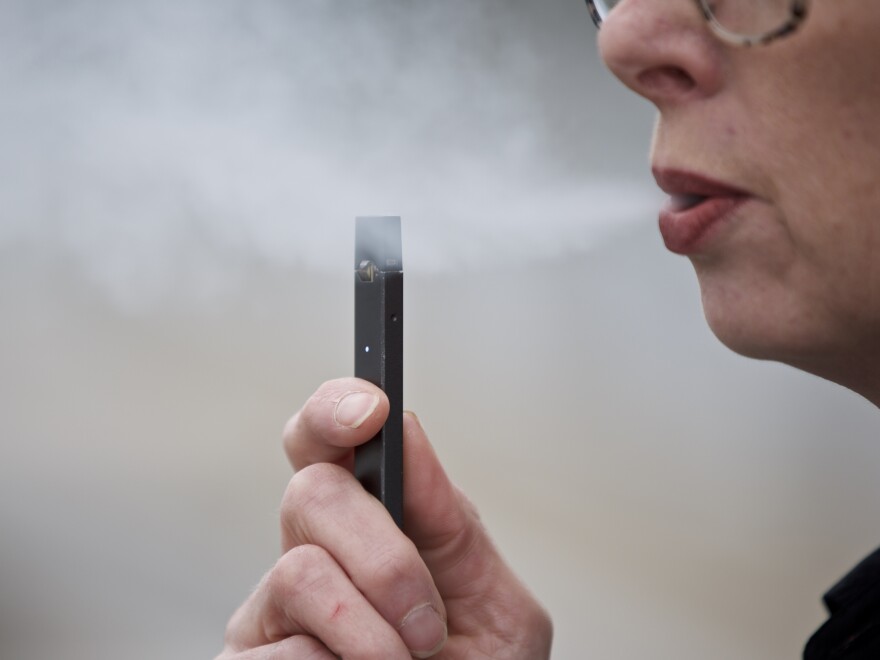 A woman exhales a puff of vapor from a Juul pen in Vancouver, Wash. Television broadcasters including Viacom, CBS and WarnerMedia announced they are no longer running e-cigarette ads.