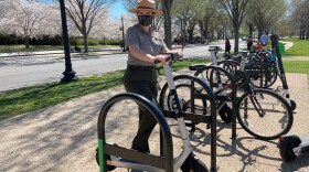 A national park ranger is holding the handlebar on an e-scooter on the National Mall in Washington D.C.