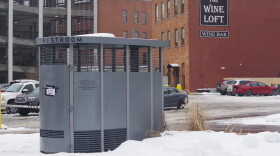 Metal stand alone bathroom in a parking lot surrounded by snow 