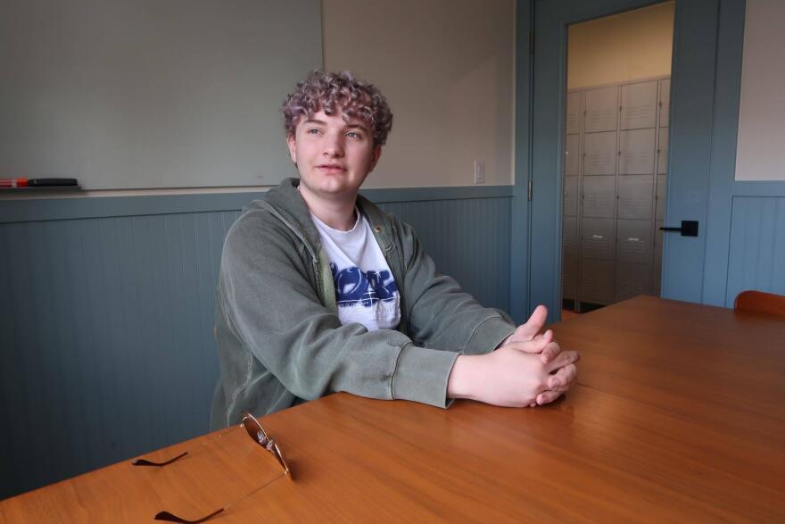Boy sits at table with fingers intertwined together
