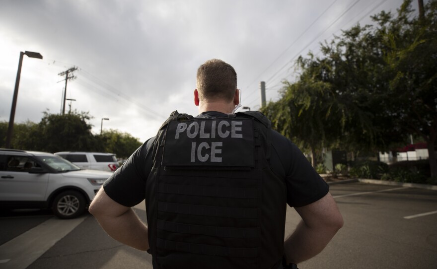 FILE - A U.S. Immigration and Customs Enforcement (ICE) officer looks on during an operation in California.