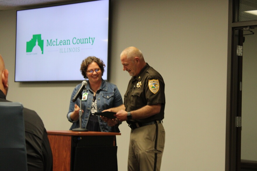 A police officer and a lady stand at a podium. 
