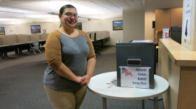 Amanda McMillon stands next to an absentee voter ballot drop box. 