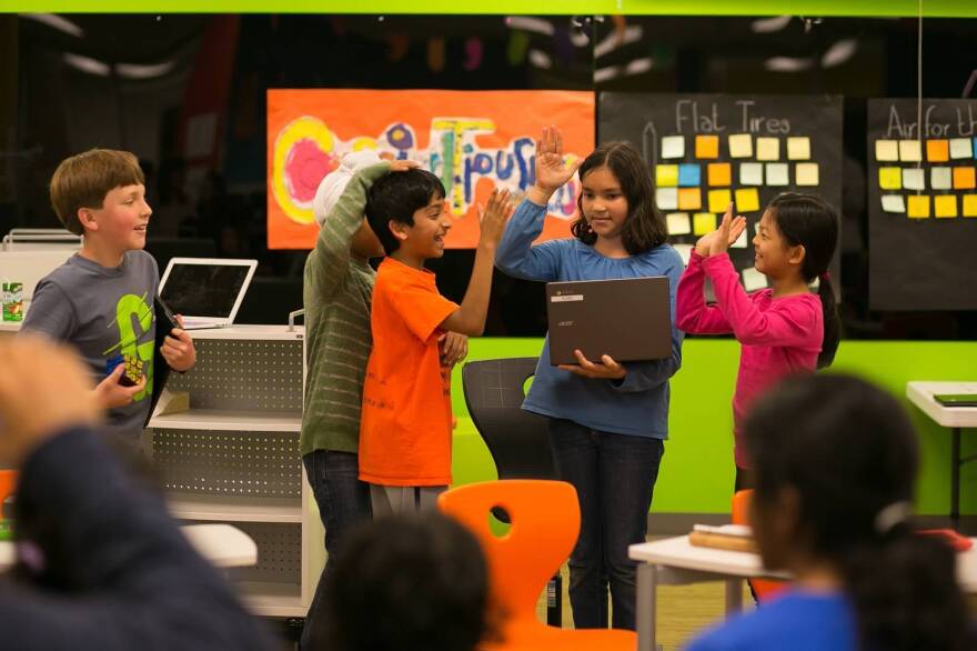 Students high-five and share a laugh at the Khan Lab School.