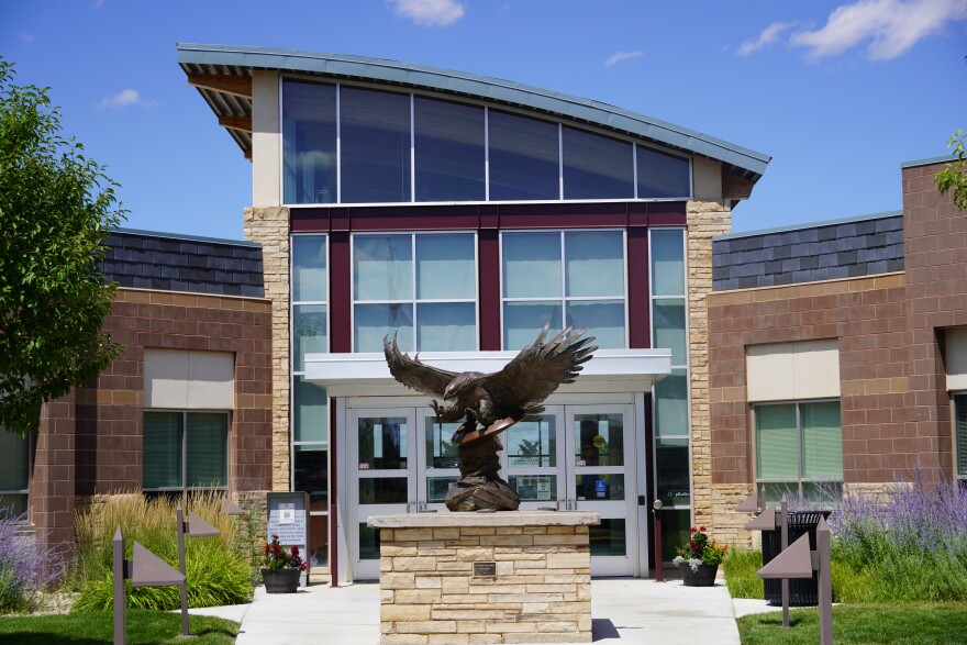 An eagle statue rises before the front doors of a modern building.