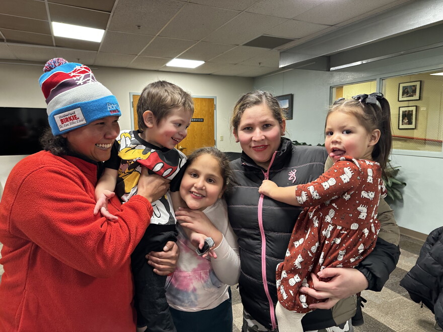 Libia Guzmán, left, beams while watching her newfound family pose for a photo on Nov. 27, 2023 at Carbondale’s Third Street Center. Guzmán is part of a group of over 100 migrants, mostly from Venezuela, who recently arrived in the Roaring Fork Valley.