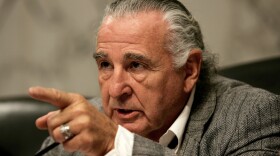 Sen. Ben Nighthorse Campbell speaks wearing a gray suit with white slicked hair.