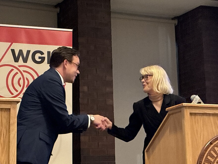 A man and a woman shake hands at a podium 