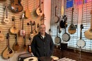 Eric Azumi stands in front of a wall of instruments at Lark in the Morning in Berkeley.