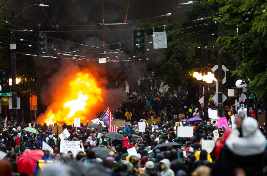 A car fire burns as protesters flood the streets of Seattle on the first day of widespread demonstrations in response to the death of George Floyd.