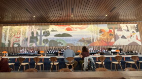 View of a restaurant bar with a painted nature mural above