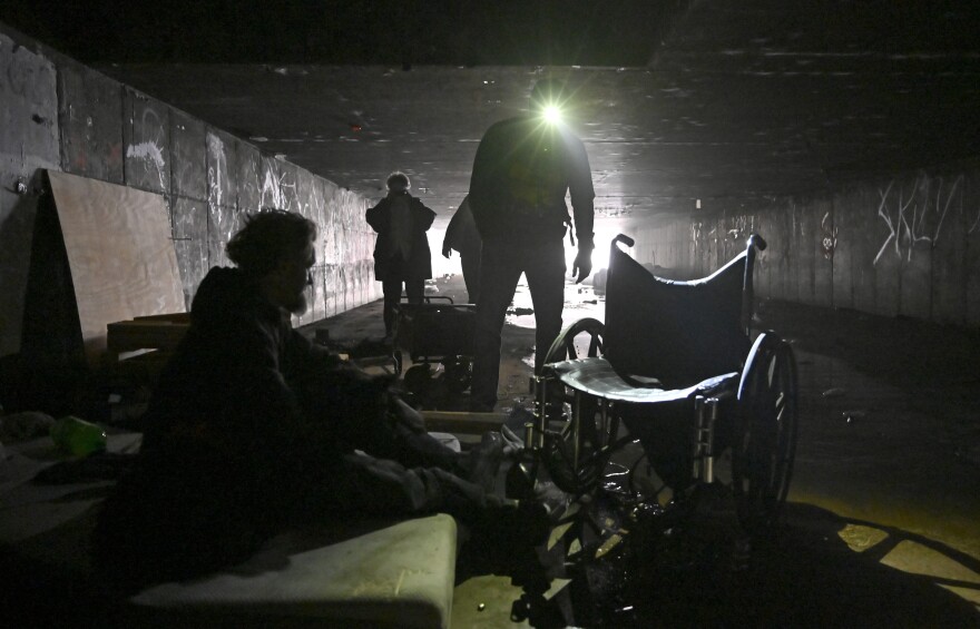 FILE - In this Dec. 5, 2020, file photo, a man who identified himself as Wheeler, left, speaks with Dave Marlon of CrossRoads of Southern Nevada, during an outreach in the underground tunnels to offer counseling, food and water to the homeless living beneath the city in Las Vegas. When census takers tried to count the nation's homeless population, they ran into many problems that could threaten the accuracy of the effort. That's what a half dozen census takers around the U.S. tell The Associated Press. (AP Photo/David Becker, File)