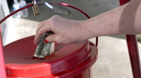 Person places dollar bill into a Salvation Army red kettle.