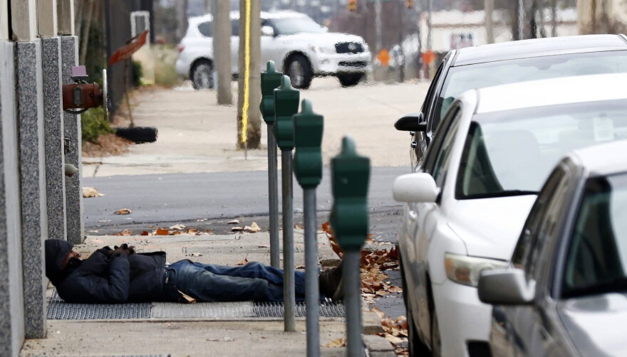 A man who is homeless takes advantage of the warm air coming from a sidewalk vent to stay warm in downtown Jackson, Miss., Wednesday, Dec. 27, 2017. (Rogelio V. Solis/AP)