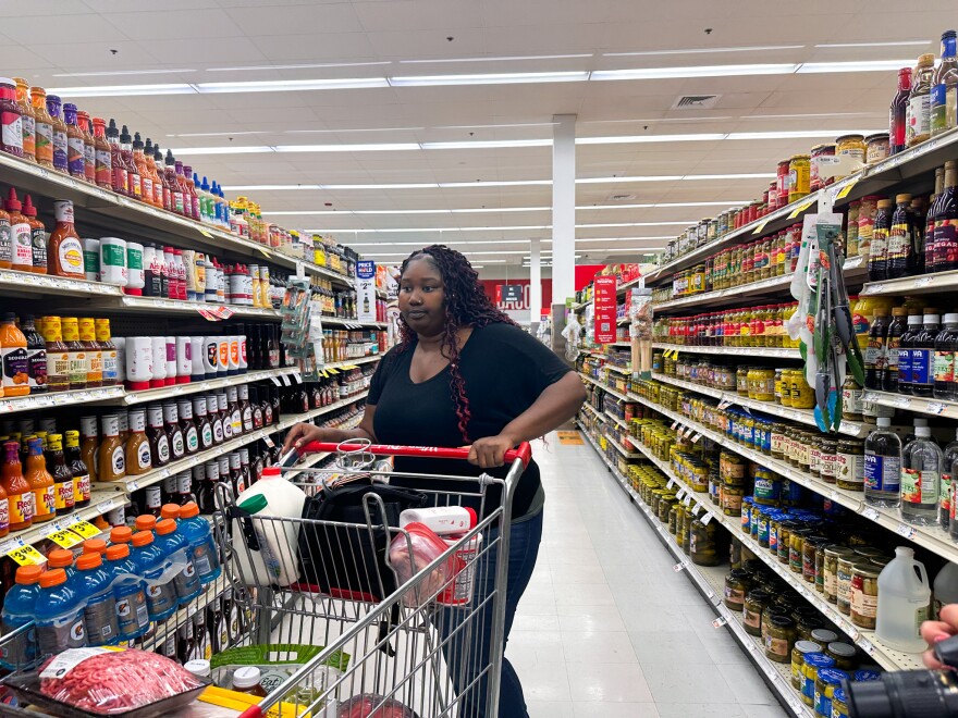 A woman pushes a cart down a dry-goods aisle at the supermarket.