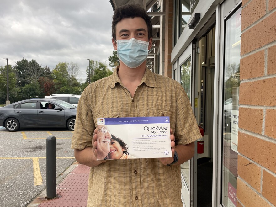 A photo of a man in a mask holding an at home test