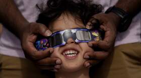 Viewers use special glasses to watch as the moon moves in front of the sun. (Eric Gay/AP)