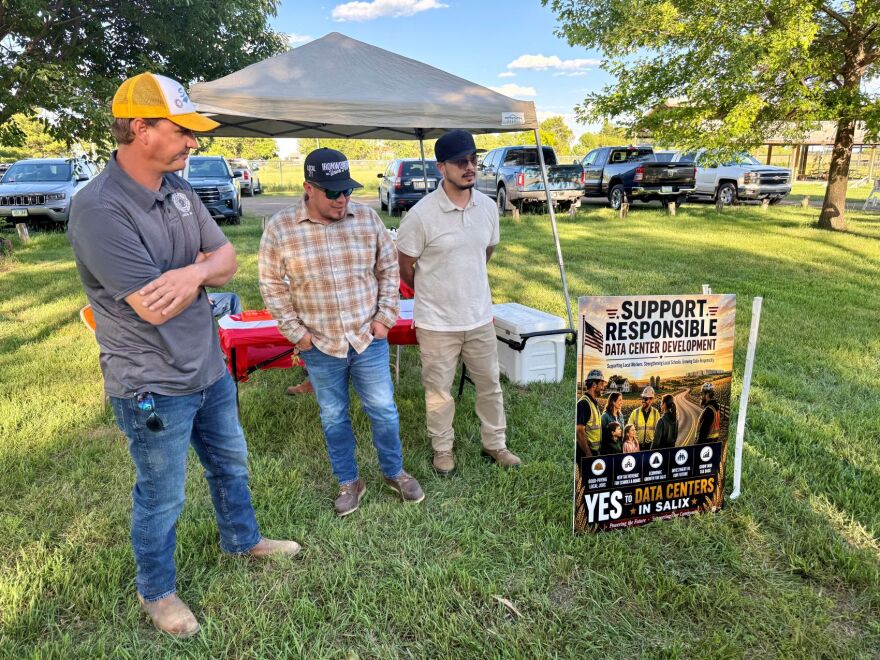 Three men wearing ball caps are standing next to a small sign to their left that says "Support responsible data center development."