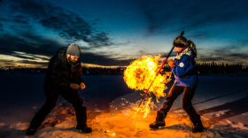 A woman holding a pole is near a fireball.